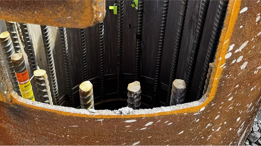 Close-up view of a rusted metal structure with exposed rebar and a rough, unfinished edge.